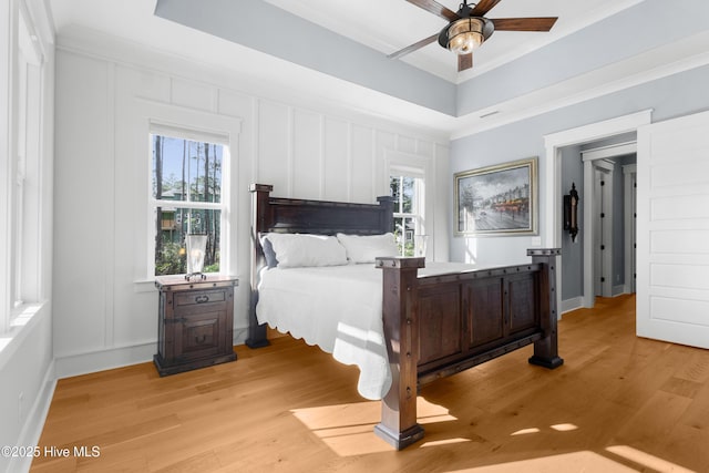 bedroom with multiple windows, ceiling fan, ornamental molding, and light hardwood / wood-style flooring