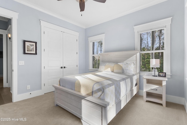 carpeted bedroom with multiple windows, ornamental molding, ceiling fan, and a closet