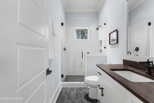 bathroom with vanity, crown molding, a shower with shower door, and toilet