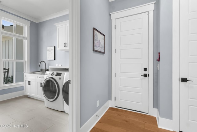 clothes washing area featuring sink, cabinets, light hardwood / wood-style flooring, ornamental molding, and washing machine and dryer