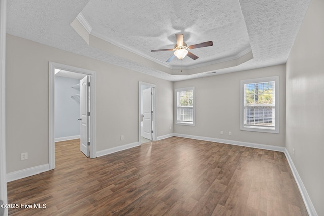 spare room featuring a tray ceiling, dark wood-type flooring, ornamental molding, and a textured ceiling