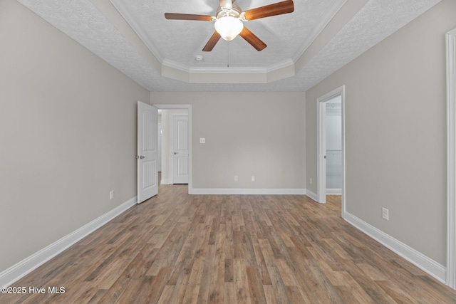 unfurnished room featuring crown molding, a textured ceiling, a raised ceiling, ceiling fan, and hardwood / wood-style floors