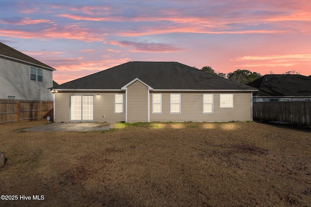 back house at dusk with a yard and a patio area