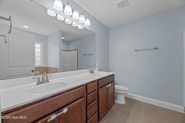 bathroom with tile patterned flooring, vanity, a textured ceiling, a shower, and toilet