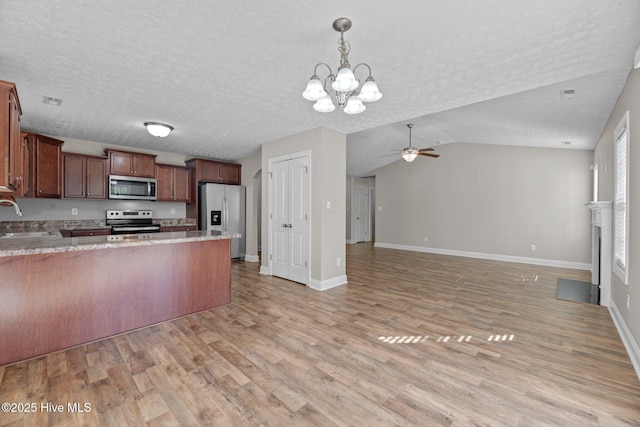 kitchen featuring decorative light fixtures, sink, light hardwood / wood-style floors, stainless steel appliances, and a textured ceiling