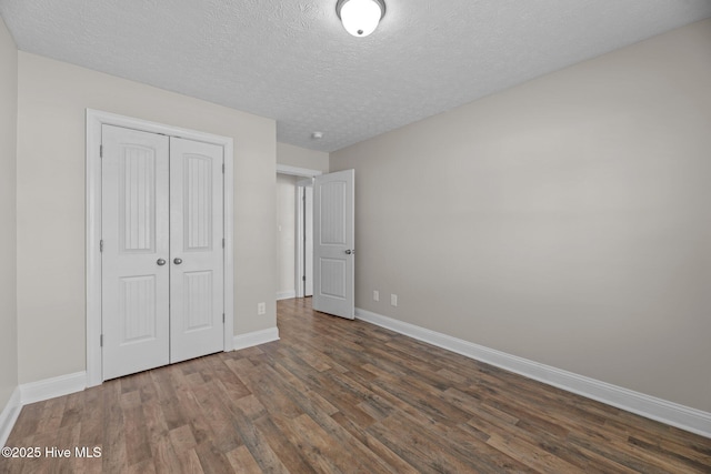 unfurnished bedroom featuring dark wood-type flooring, a closet, and a textured ceiling