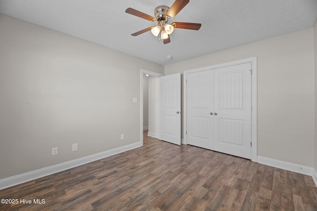 unfurnished bedroom featuring a closet, dark hardwood / wood-style floors, a textured ceiling, and ceiling fan