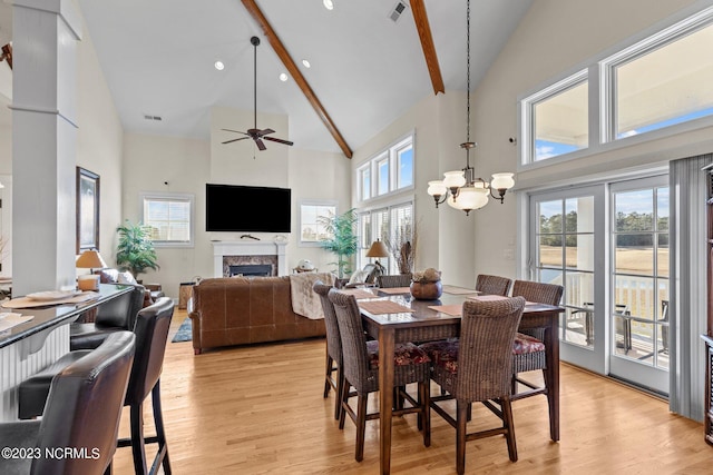 dining space featuring high vaulted ceiling, light hardwood / wood-style floors, beam ceiling, and ceiling fan with notable chandelier