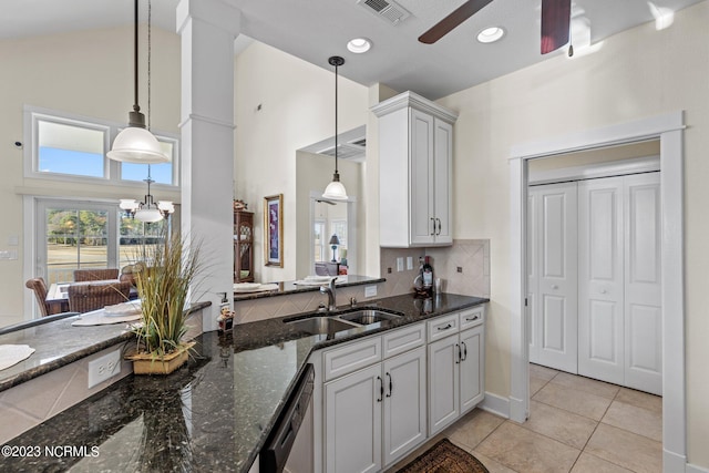 kitchen featuring stainless steel dishwasher, hanging light fixtures, sink, white cabinetry, and dark stone counters