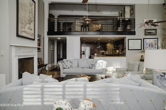 living room featuring ceiling fan, wood-type flooring, and a high end fireplace