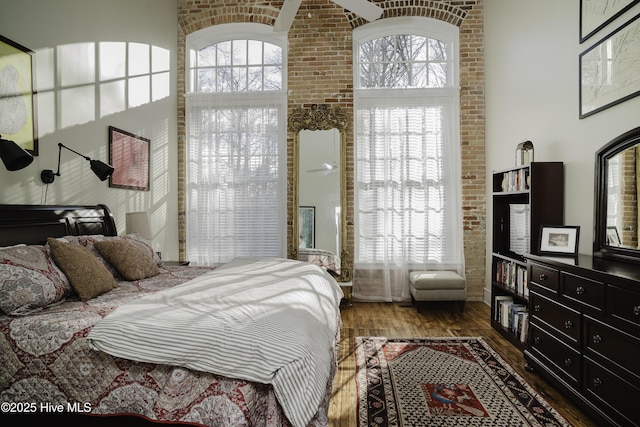 bedroom with dark hardwood / wood-style floors and brick wall