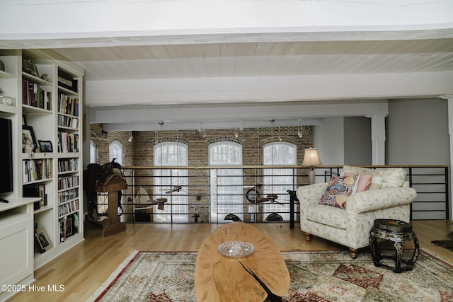 sitting room featuring wooden ceiling, brick wall, light hardwood / wood-style flooring, and beamed ceiling