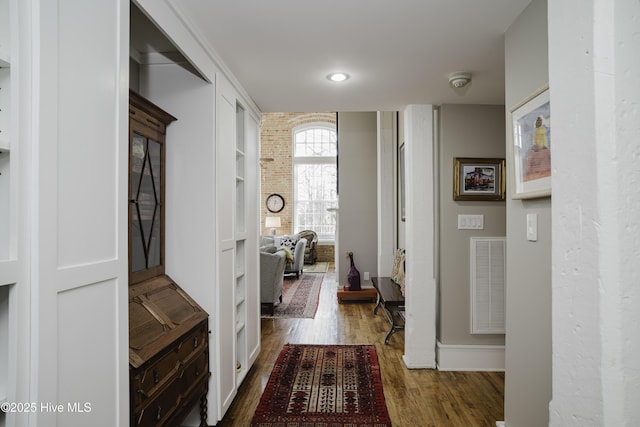 hallway featuring wood-type flooring and brick wall