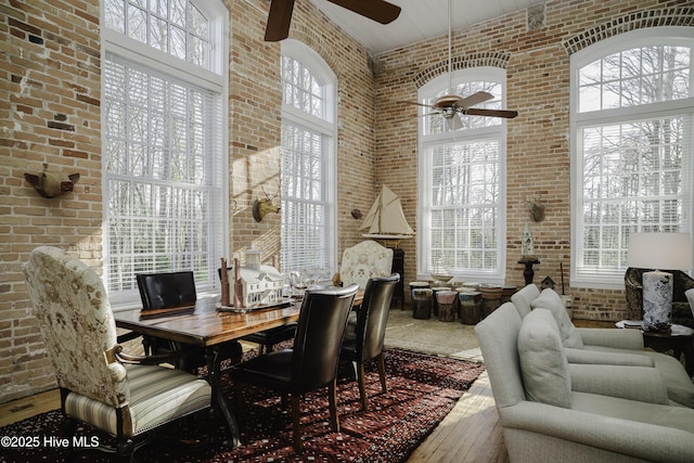 dining room with a wealth of natural light, wood-type flooring, and brick wall