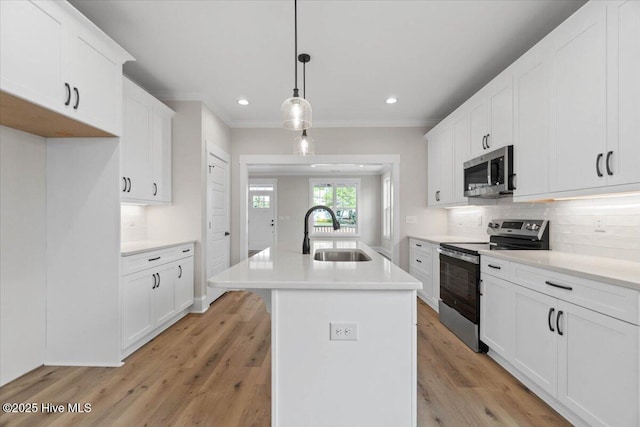 1665 Butterfly Knot Dr SW, Ocean Isle Beach, NC 28469 - kitchen with stainless steel appliances, a sink, tasteful backsplash, light wood finished floors, and an island with sink