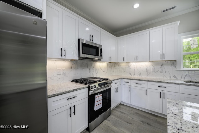 682 Crump Farm Rd, New Bern, NC 28562 - kitchen with decorative backsplash, crown molding, visible vents, white cabinets, and appliances with stainless steel finishes