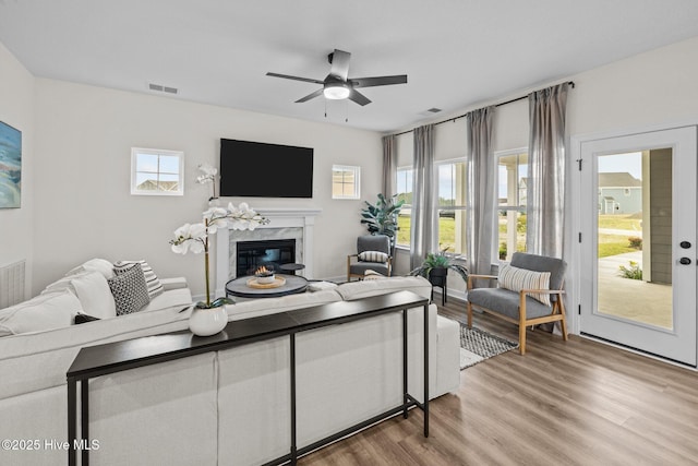 living room featuring ceiling fan, hardwood / wood-style floors, and a fireplace