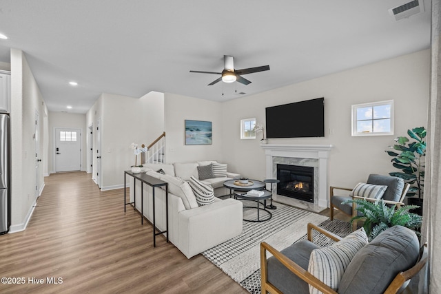 living room with ceiling fan, light hardwood / wood-style floors, and a fireplace