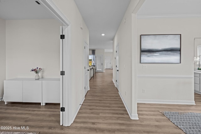 corridor with ornamental molding and hardwood / wood-style floors