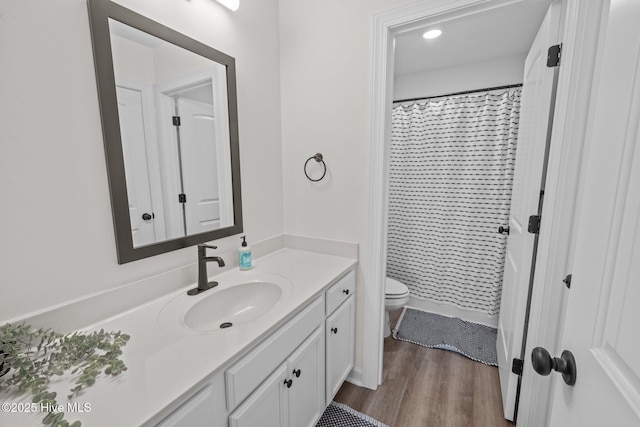 bathroom featuring toilet, vanity, wood-type flooring, and walk in shower