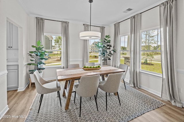 dining area with light wood-type flooring and crown molding