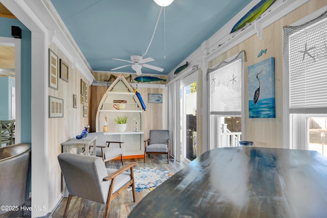 sitting room featuring wood-type flooring, ceiling fan, crown molding, and wood walls