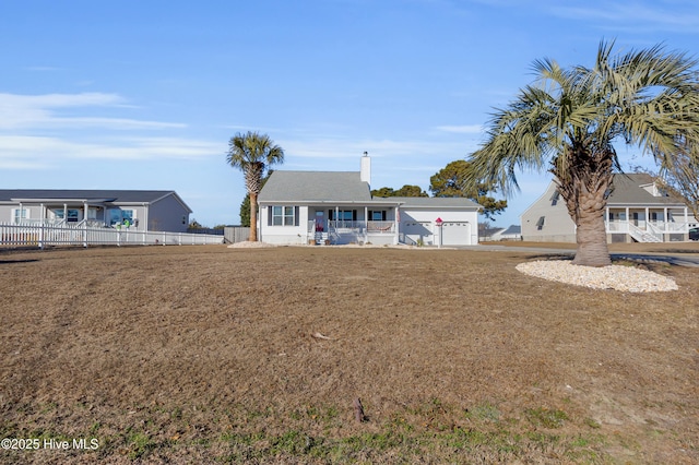 back of house featuring a garage, covered porch, and a lawn