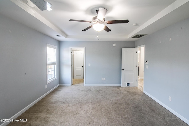 unfurnished bedroom with a raised ceiling, light colored carpet, visible vents, and baseboards