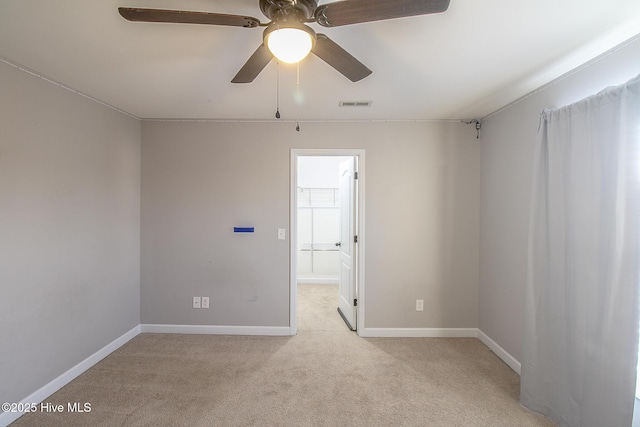 spare room featuring light colored carpet, visible vents, ceiling fan, and baseboards