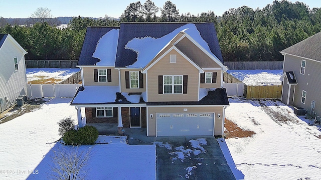 traditional-style home with a garage, covered porch, driveway, and fence