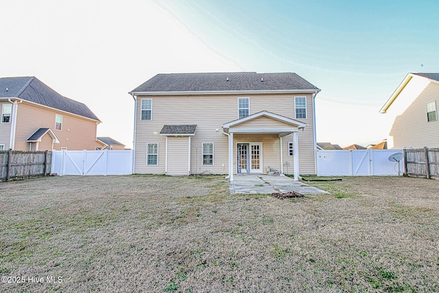 back of house featuring a gate, a fenced backyard, a patio, and a lawn