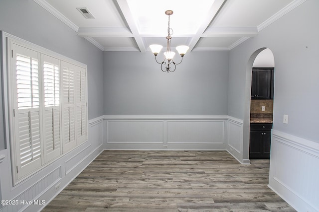 unfurnished room with arched walkways, visible vents, coffered ceiling, beamed ceiling, and wood finished floors