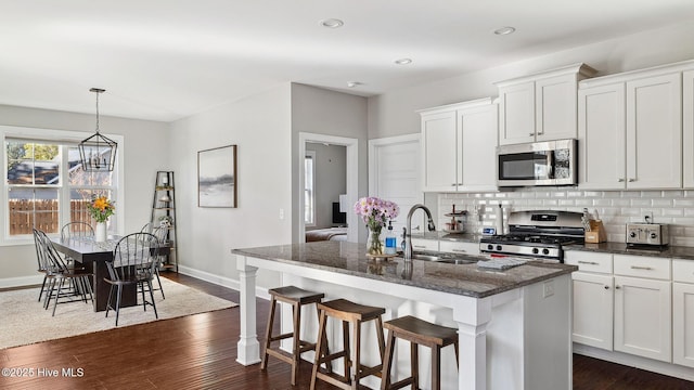 kitchen with white cabinetry, appliances with stainless steel finishes, sink, and an island with sink