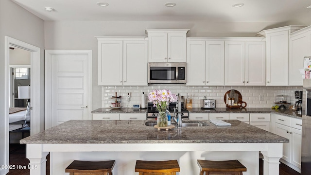 kitchen featuring a kitchen bar, a center island with sink, and appliances with stainless steel finishes