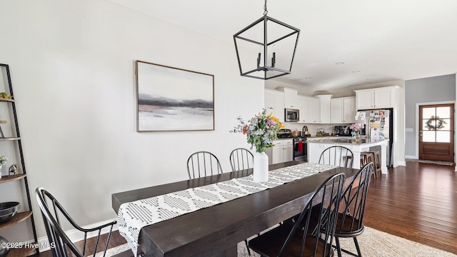 dining area with dark hardwood / wood-style floors and a notable chandelier