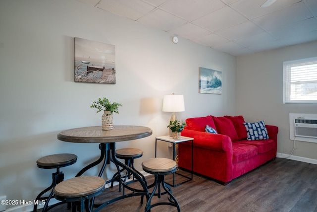 living room with a drop ceiling, dark hardwood / wood-style floors, and a wall mounted AC