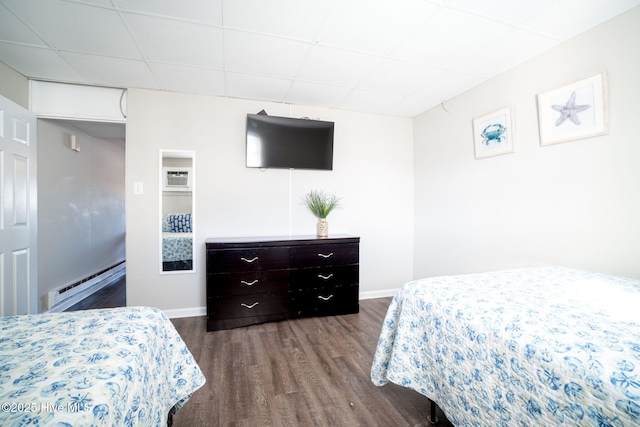 bedroom featuring a baseboard radiator, a paneled ceiling, hardwood / wood-style floors, and a wall unit AC