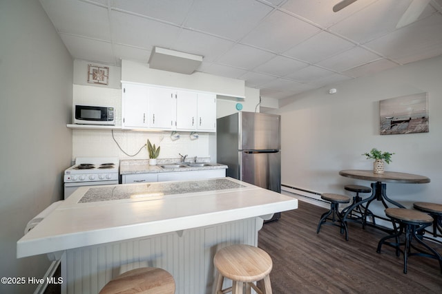 kitchen with sink, white cabinets, dark hardwood / wood-style flooring, a kitchen breakfast bar, and white range with electric cooktop