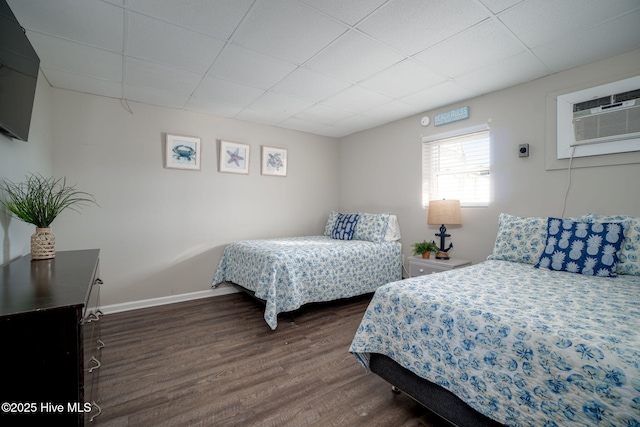 bedroom featuring dark hardwood / wood-style flooring, a drop ceiling, and an AC wall unit