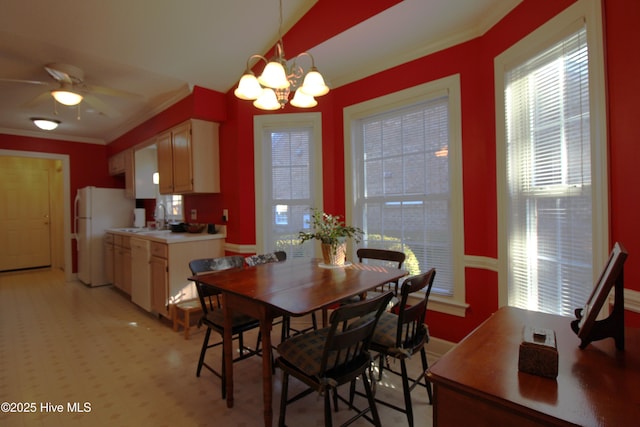 dining space with ceiling fan with notable chandelier, sink, and ornamental molding