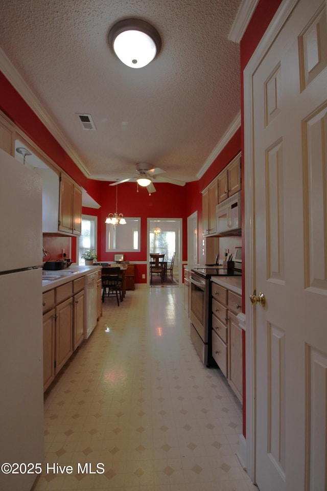 kitchen featuring decorative light fixtures, white appliances, light brown cabinetry, and a textured ceiling