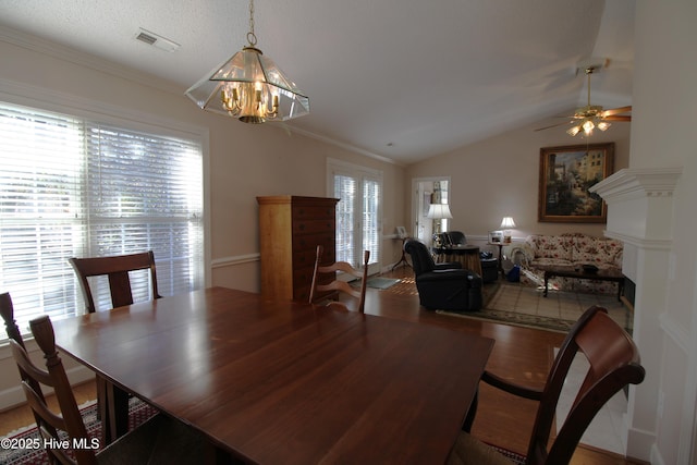 dining area with hardwood / wood-style floors, ceiling fan with notable chandelier, lofted ceiling, and ornamental molding