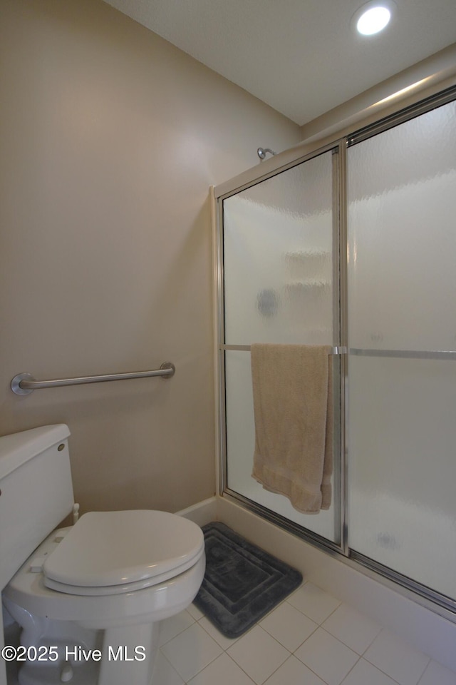 bathroom with tile patterned floors, a shower with door, and toilet