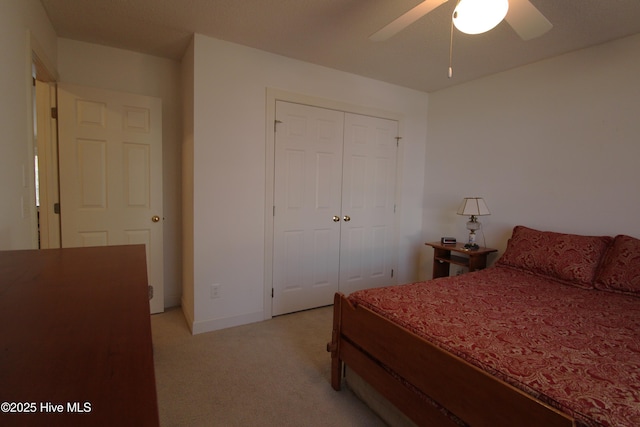 bedroom featuring light colored carpet, a closet, and ceiling fan