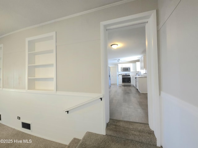 stairway featuring carpet floors, built in features, and ornamental molding