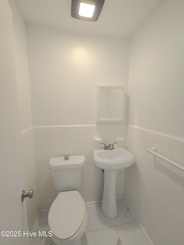 bathroom with toilet and tile walls