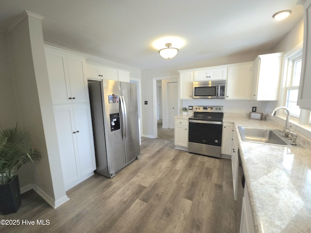 kitchen featuring light stone countertops, hardwood / wood-style floors, white cabinets, stainless steel appliances, and sink