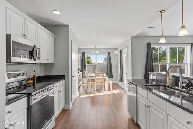 kitchen featuring appliances with stainless steel finishes, decorative light fixtures, white cabinetry, sink, and plenty of natural light