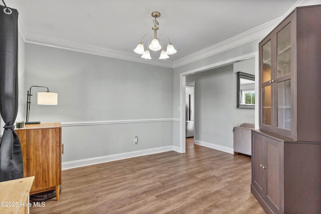 unfurnished dining area with a chandelier, ornamental molding, and wood-type flooring