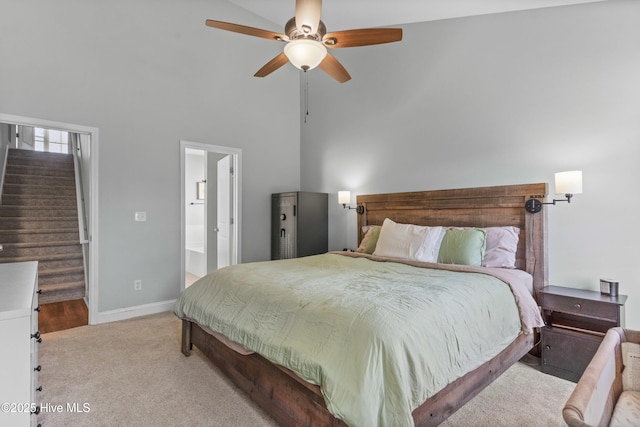 carpeted bedroom with ceiling fan, high vaulted ceiling, and ensuite bath